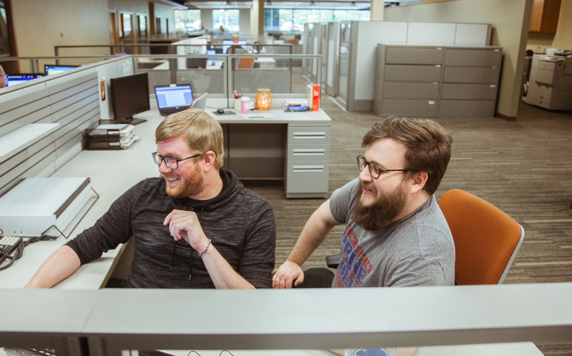 Two men working a cubical.
